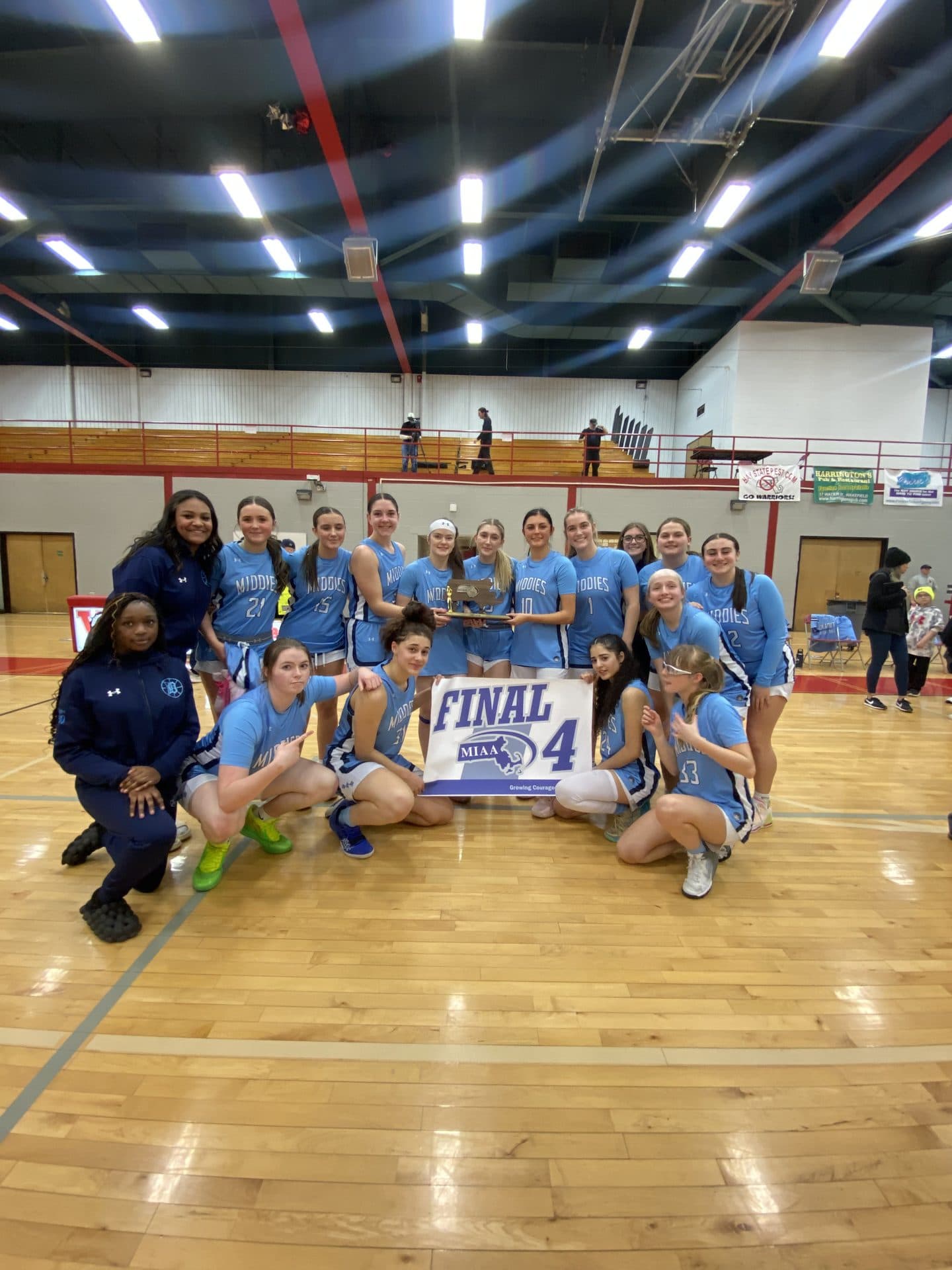 Dracut Middies girls basketball team with their MIAA Final Four banner